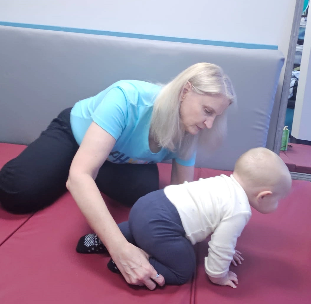 Child balancing on therapy beam with therapist support