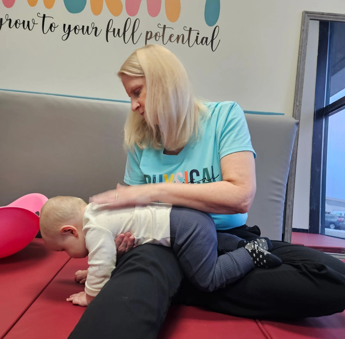 Parent gently massaging baby’s legs during therapy session